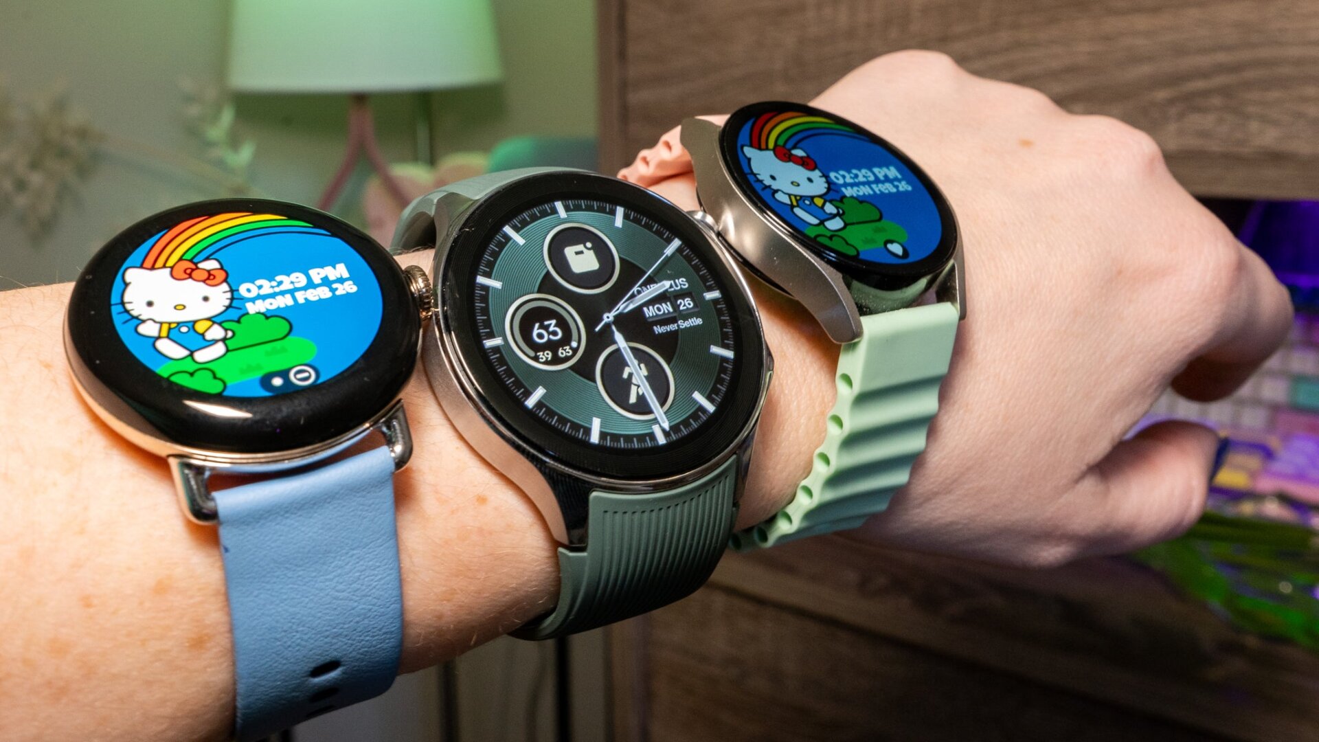 La Google Pixel Watch 2 (à gauche), la OnePlus Watch 2 (au milieu) et la Galaxy Watch 6 (à droite) tous entassés sur le  les petits poignets de l’auteur.