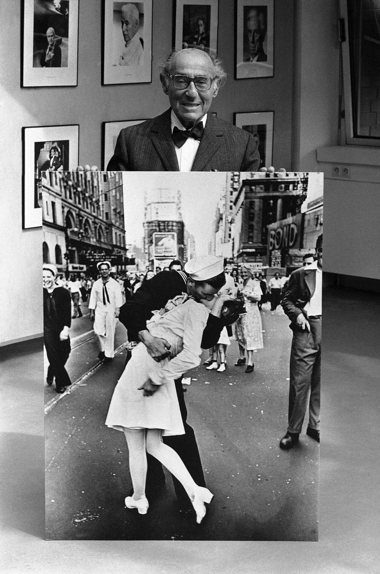 Le photographe et photojournaliste germano-américain Alfred Eisenstaedt pose lors de l’ouverture, le 5 mai 1986, d’une exposition de ses célèbres photos prises pour Vie magazine au Kultur Kontor der Hamburger  Hanse Vier, à Hambourg, en Allemagne, avec l’une de ses photos les plus connues prises pendant la  célébrations du VJ Day à Times Square, New York, en août 1945. 