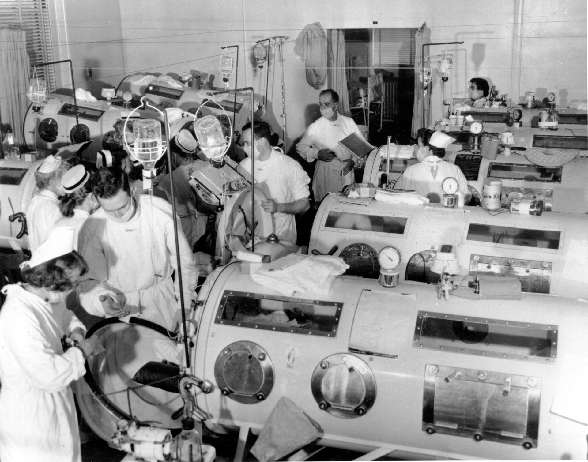 Il s’agit d’une scène dans le service d’urgence de la polio de l’hôpital Haynes Memorial à Boston, Massachusetts, le 16 août 1955. L’épidémie de polio a atteint un maximum de 480 cas. Les patients dans un état critique sont alignés les uns à côté des autres dans des respirateurs à poumons de fer, de sorte qu’un Une équipe de médecins et d’infirmières peut administrer un traitement d’urgence rapide si nécessaire. 