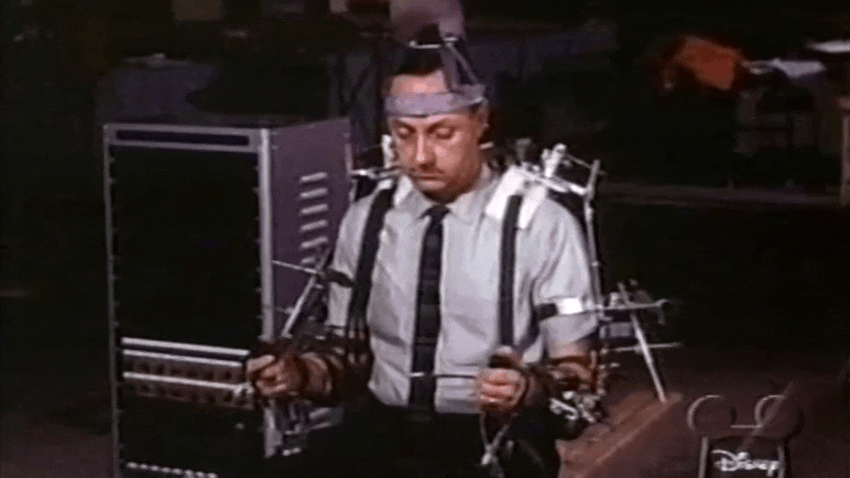Un robot du Carrousel du Progrès de l’Exposition mondiale de 1964 est présenté par Walt Disney et un ingénieur à l’aide d’un dispositif de manipulation de style waldo. 