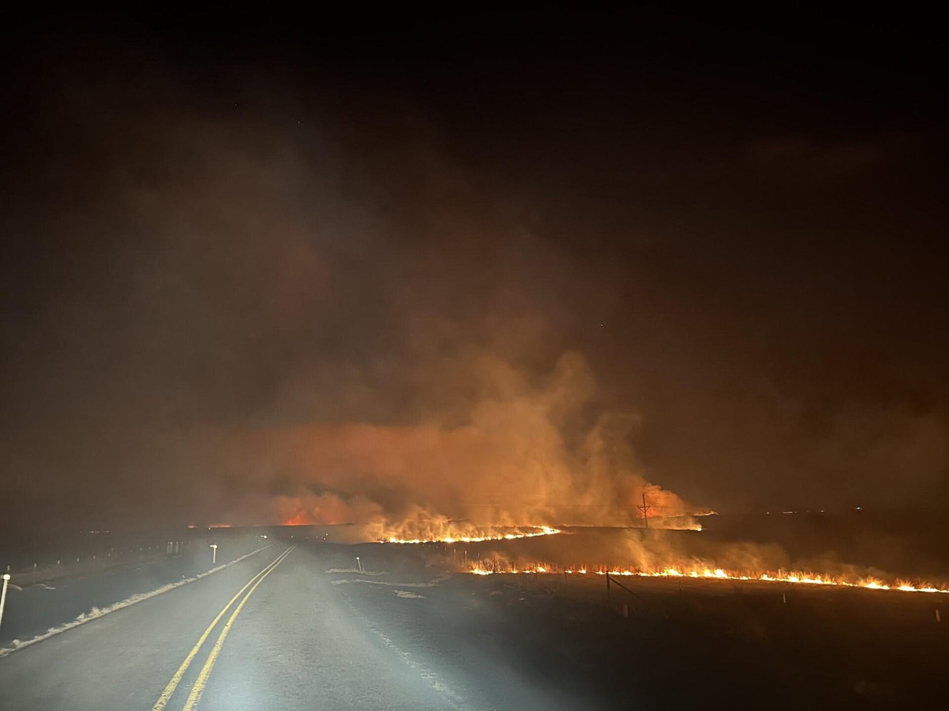   Dans cette photo fournie par le Texas A&M Forest Service, un feu traverse une route dans l’incendie de Smokehouse Creek le soir. du 27 février 2024, dans l’enclave du Texas. 