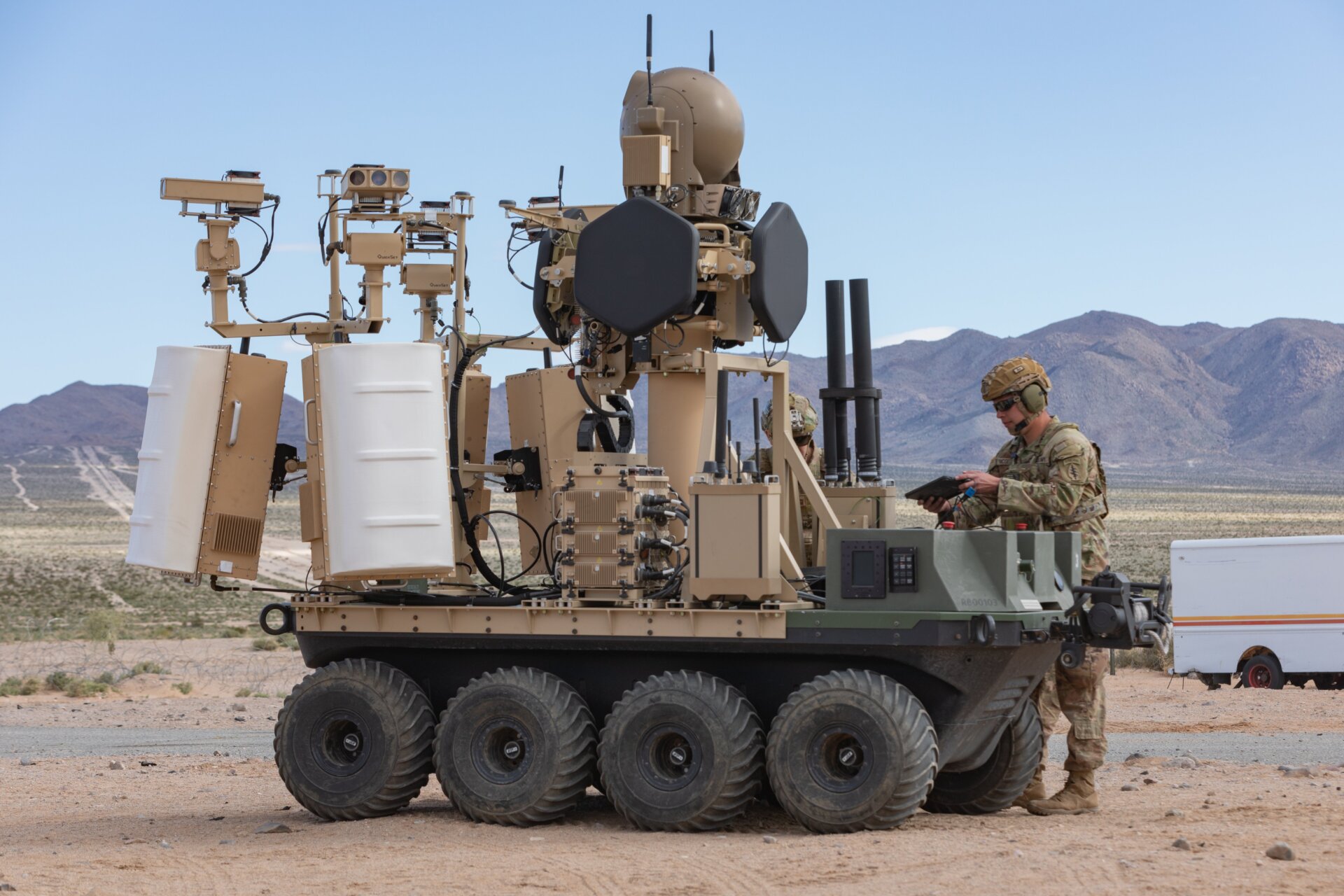 Une plate-forme tout-terrain sans pilote, à huit roues, entièrement électrique, de l’armée américaine, dotée d’un système UAS modulaire de contre-petite avec un humain dans le Le système opérationnel en boucle de la famille des systèmes de contre-attaque sans pilote ou FoCUS fournit un soutien aux soldats débarqués dans un environnement d’entraînement urbain dans le cadre d’une expérience d’intégration humaine à Fort Irwin, Californie, 18  mars 2024. 