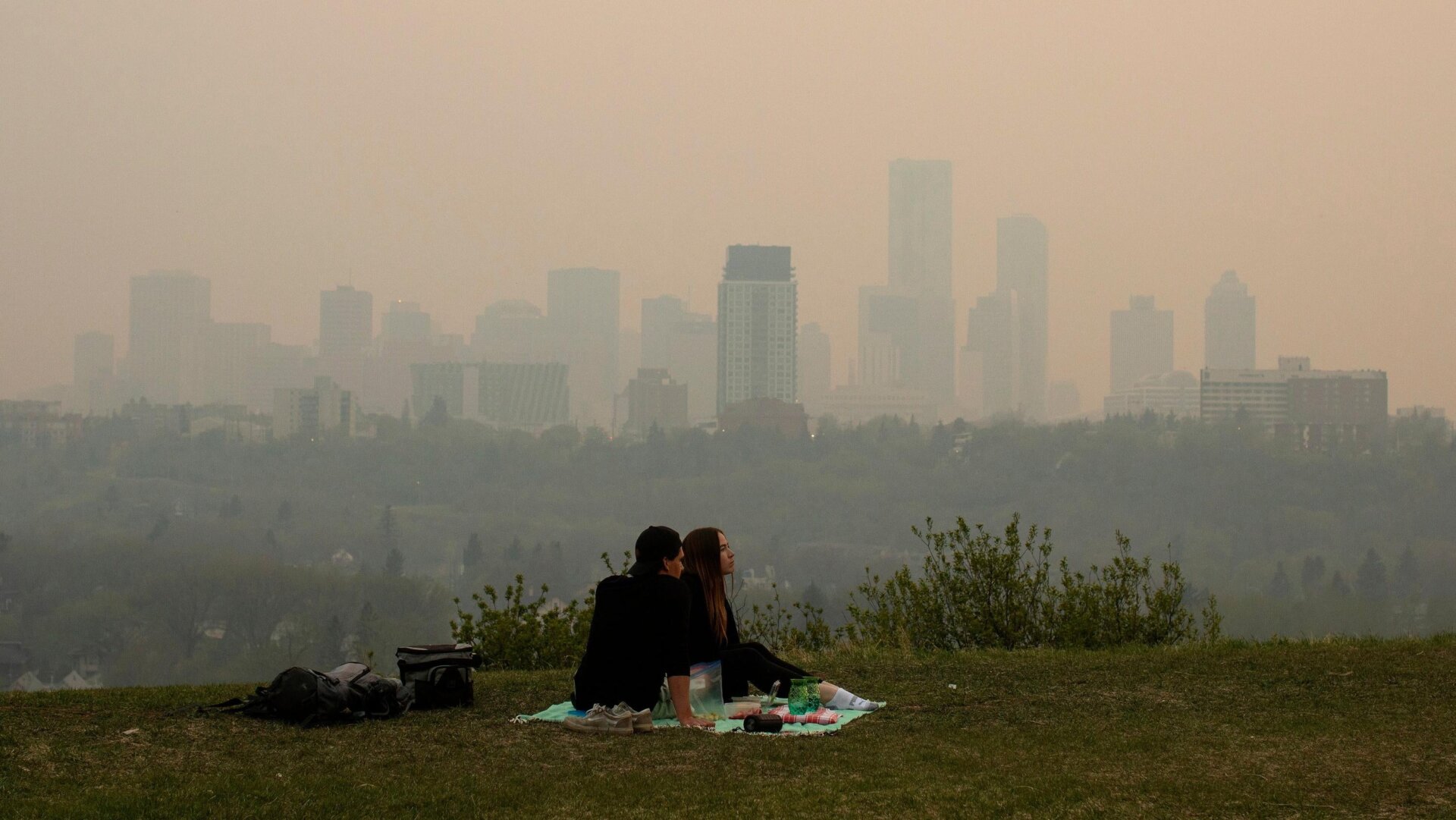 La fumée des feux de forêt recouvre la ville alors qu’un couple organise un pique-nique à Edmonton, en Alberta, le 11 mai 2024.