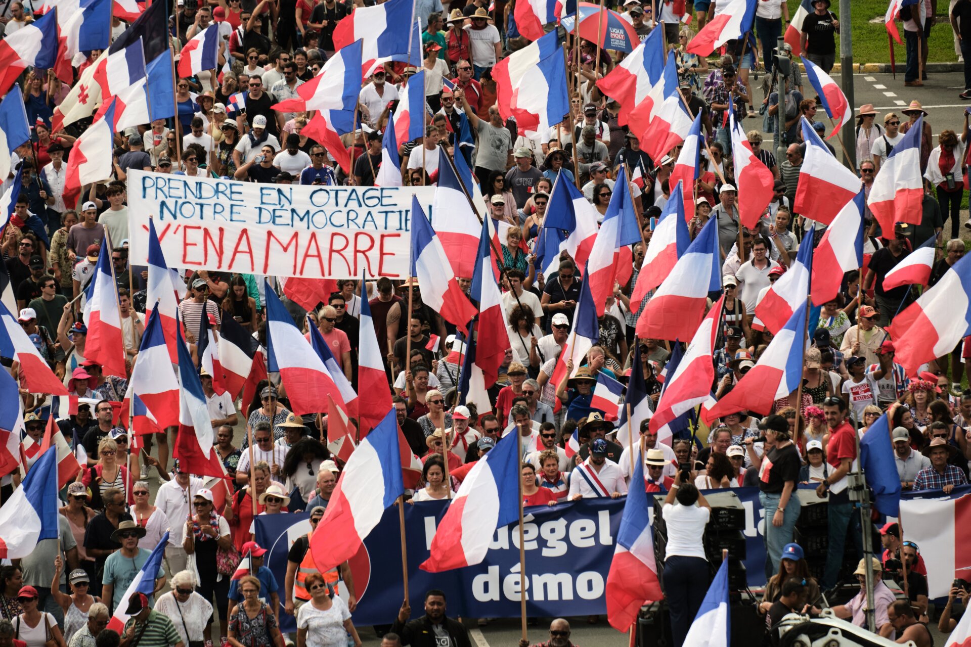 Des manifestants de plusieurs partis loyalistes brandissent des drapeaux nationaux français et tiennent une banderole sur laquelle est écrit «&nbsp;Prendre en otage notre démocratie y’en a marre&nbsp;». (Enlevez-vous notre démocratie) alors qu’ils défilent lors d’une manifestation pour soutenir l’élargissement de l’électorat pour les prochaines élections provinciales. élections en Nouvelle Calédonie, à Nouméa, le 13 avril 2024. 