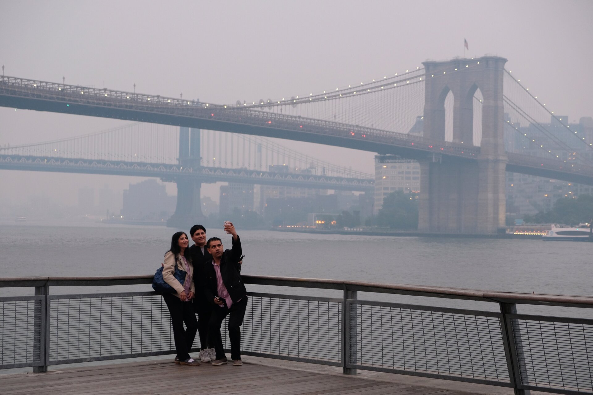 Un groupe prend un selfie avec en arrière-plan le pont de Manhattan et  le pont de Brooklyn, à New York le mercredi 7 juin   2023