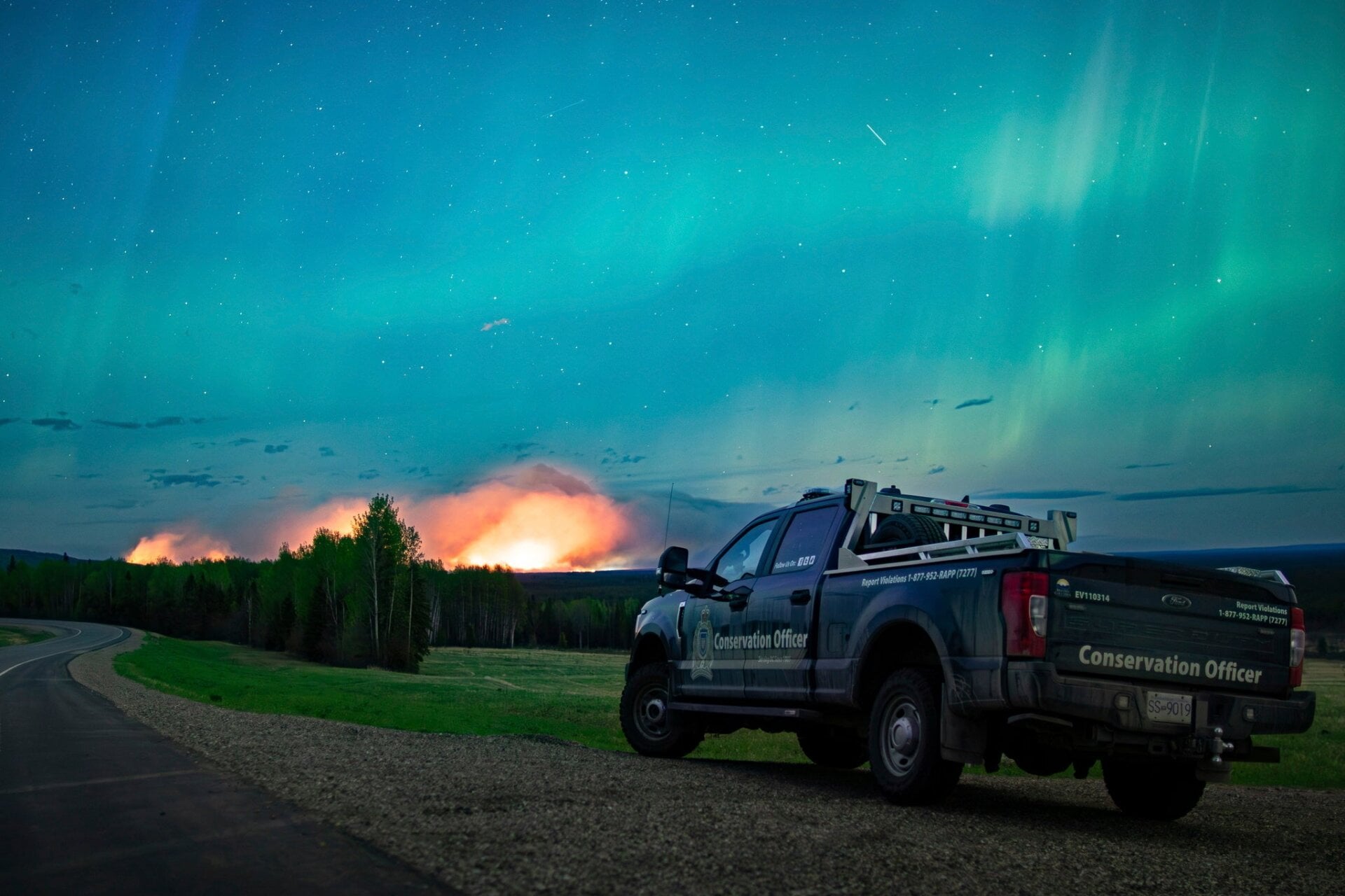 Cette photo fournie par le ministère de l’Eau, des Terres et de Gérance des ressourcesmontre un incendie de forêt, une aurore boréale au-dessus, près de Fort  Nelson, en British  Colombie samedi, 11 mai 2024. 